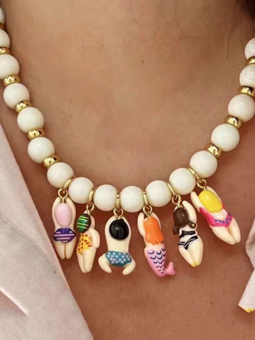 White Beaded Necklace with Gold Accents and Multicolor Swimmer Charms